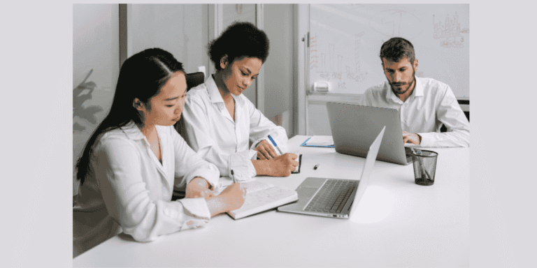 Professional team meeting with diverse colleagues working on laptops in modern office workspace"